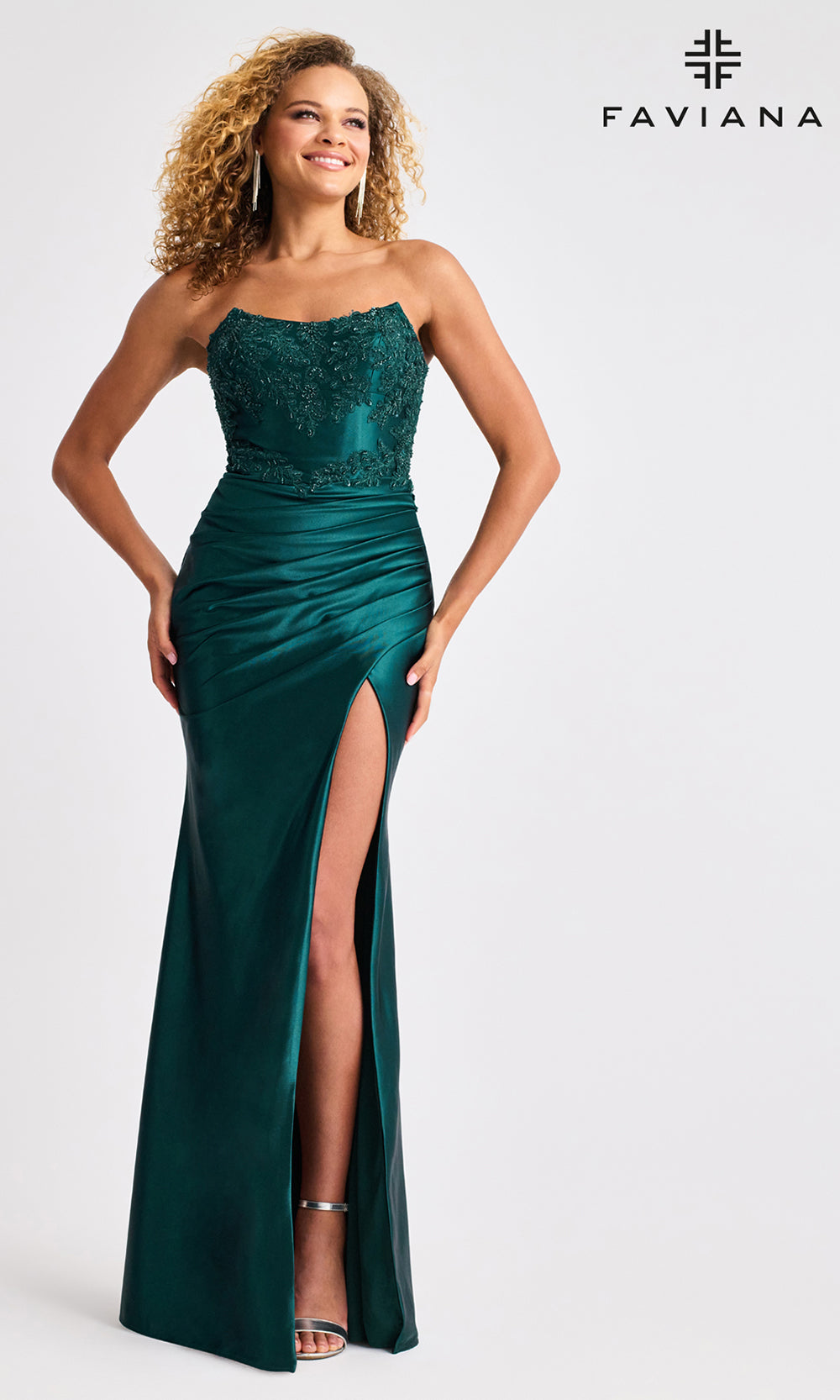 Woman wearing a green evening gown with a high slit, standing against a white background with 'Faviana' branding.