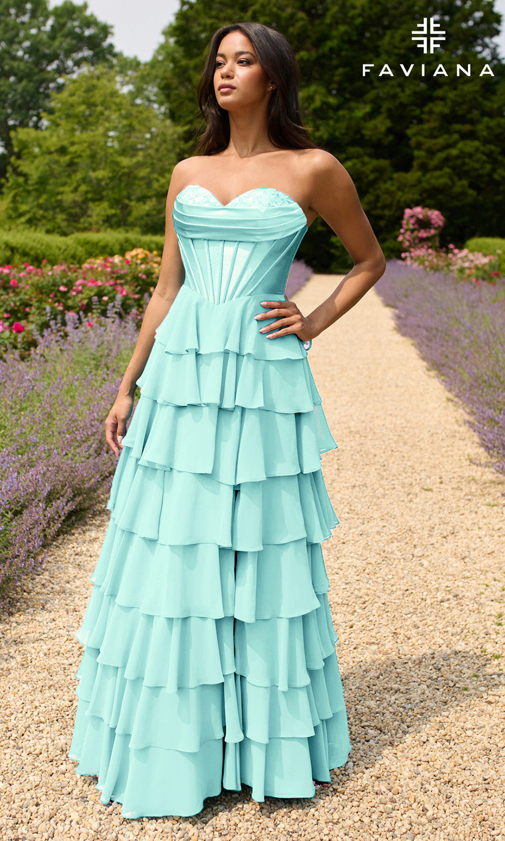 Woman wearing a light blue strapless gown with ruffled layers in a garden setting, with 'Faviana' branding.
