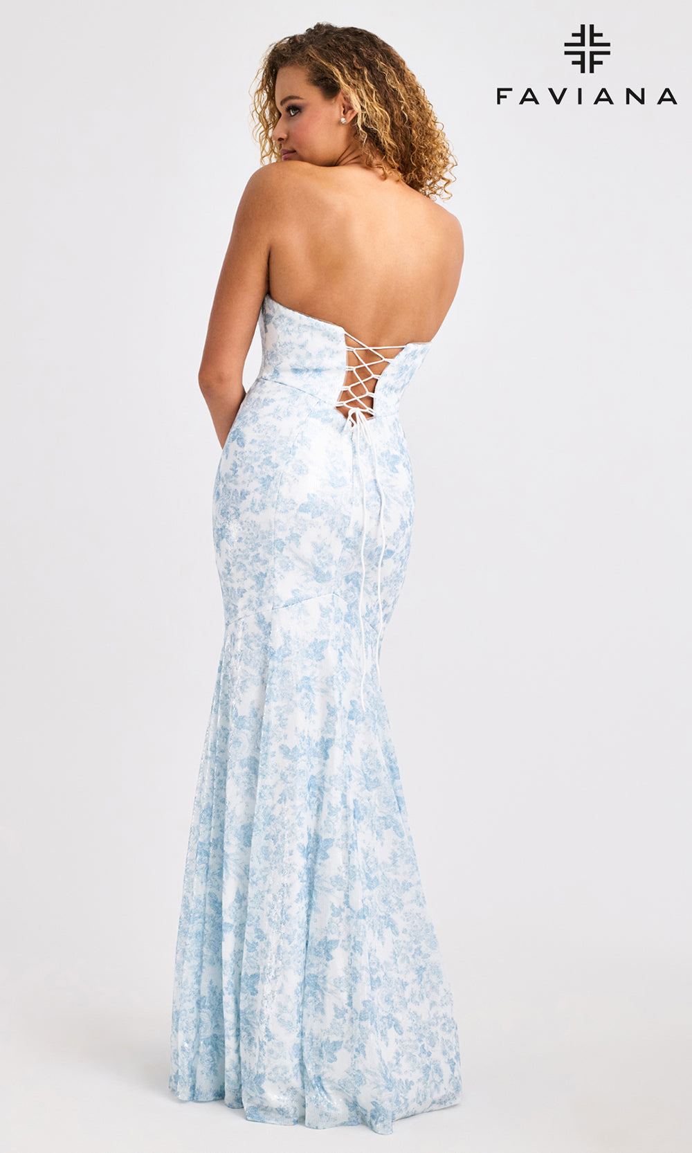 Woman wearing a light blue strapless dress with lace-up back, branded 'Faviana'.
