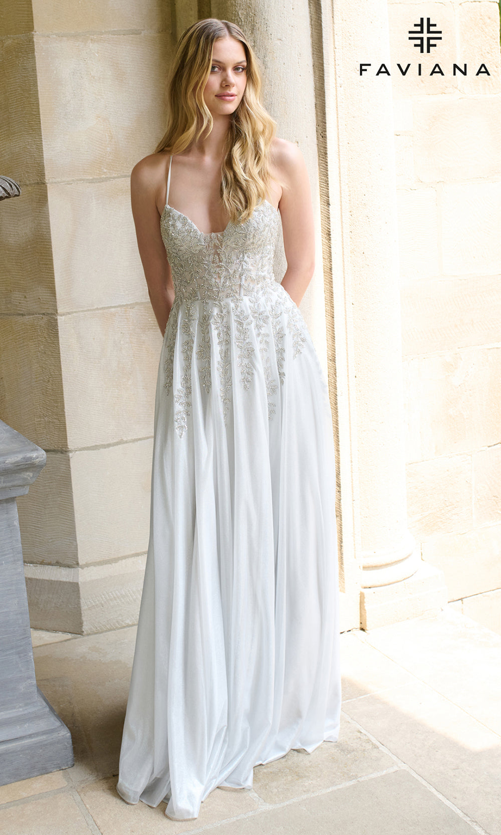 Woman wearing a white evening gown with Faviana branding in the corner.