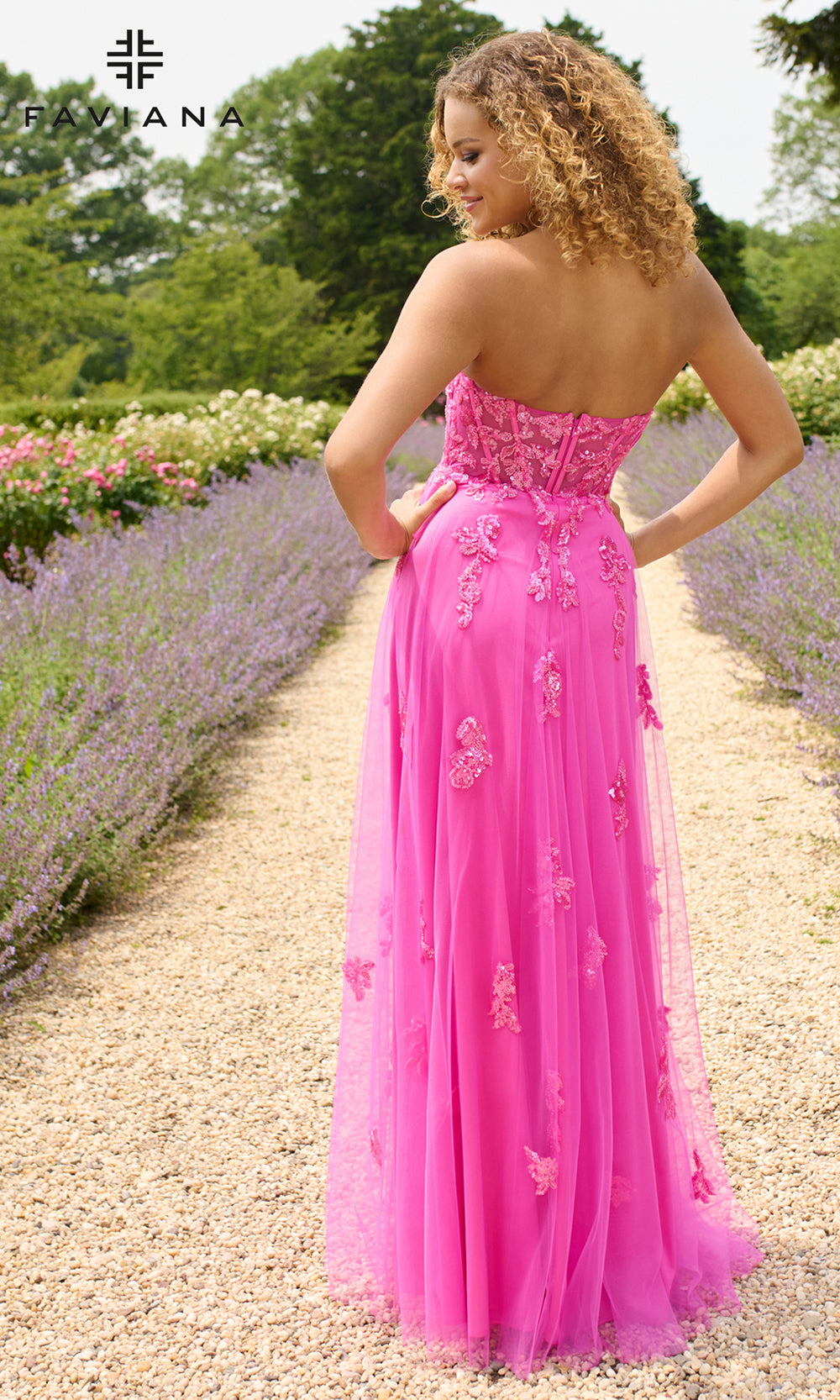 Woman in a pink dress standing in a garden with lavender and flowers.
