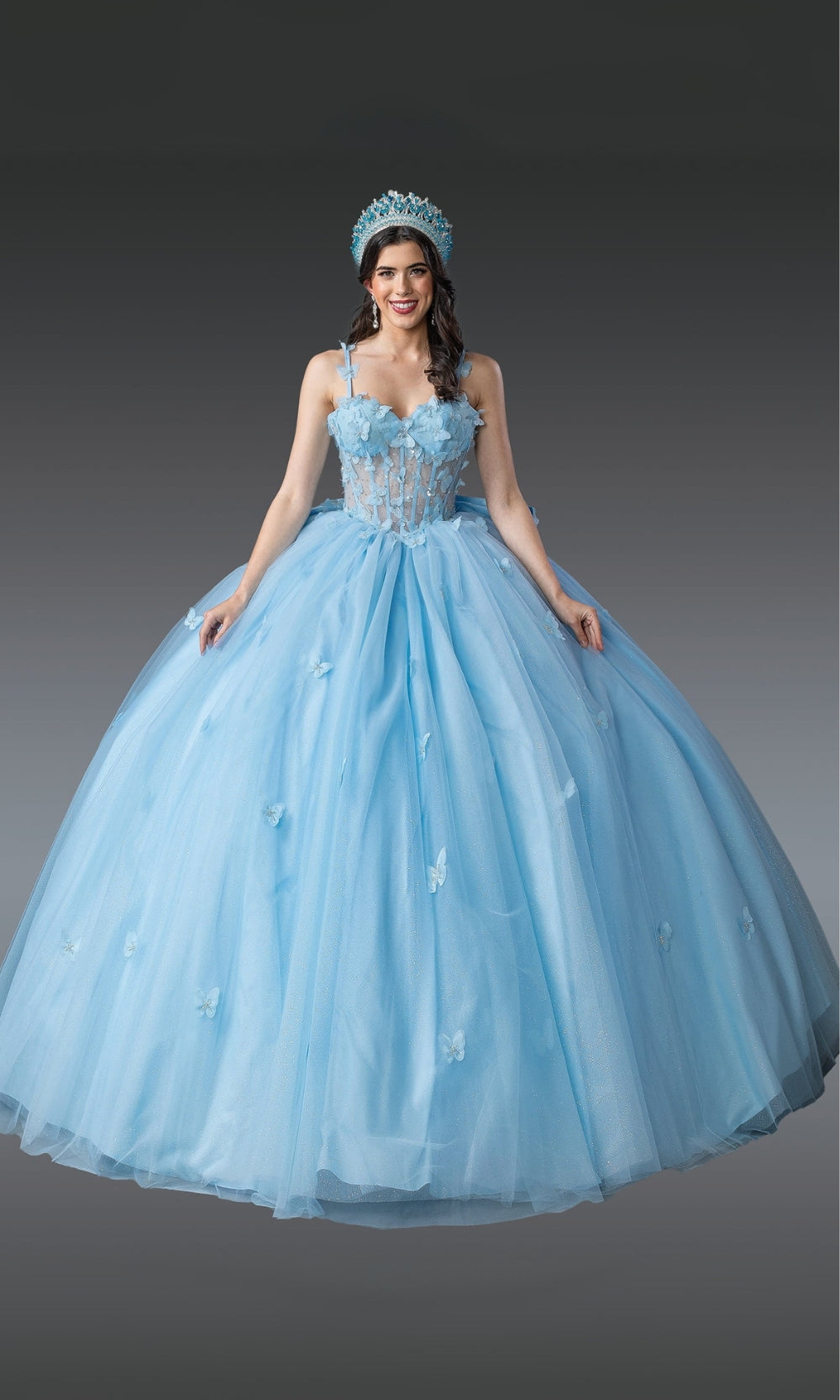 Woman wearing a light blue ball gown with a matching headpiece on a gray background