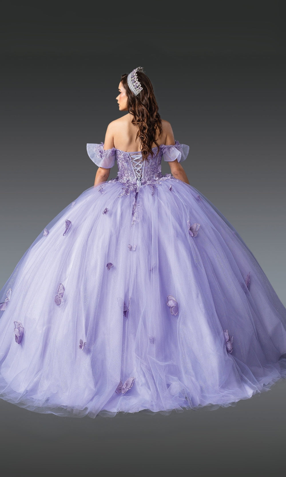 Woman wearing a purple off-shoulder gown with floral details on a gray background