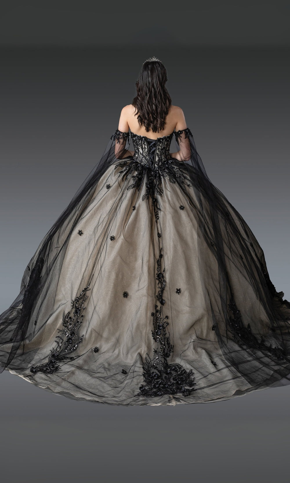 Woman wearing a black and gray gown with intricate designs on a gray background