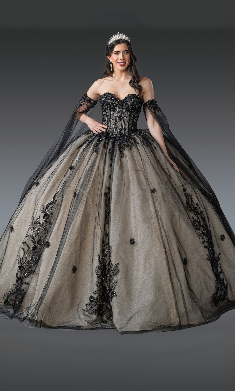 Woman wearing a black and beige ball gown with intricate detailing on a gray background