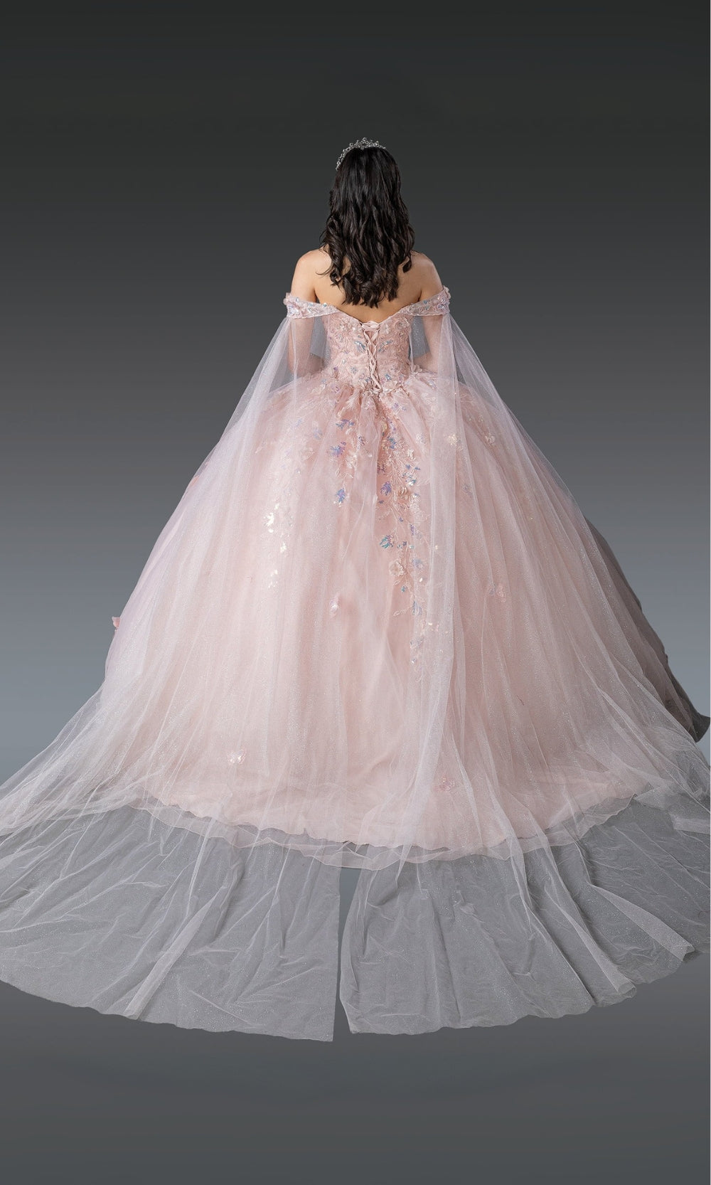 Pink off-shoulder gown with a long train on a dark background