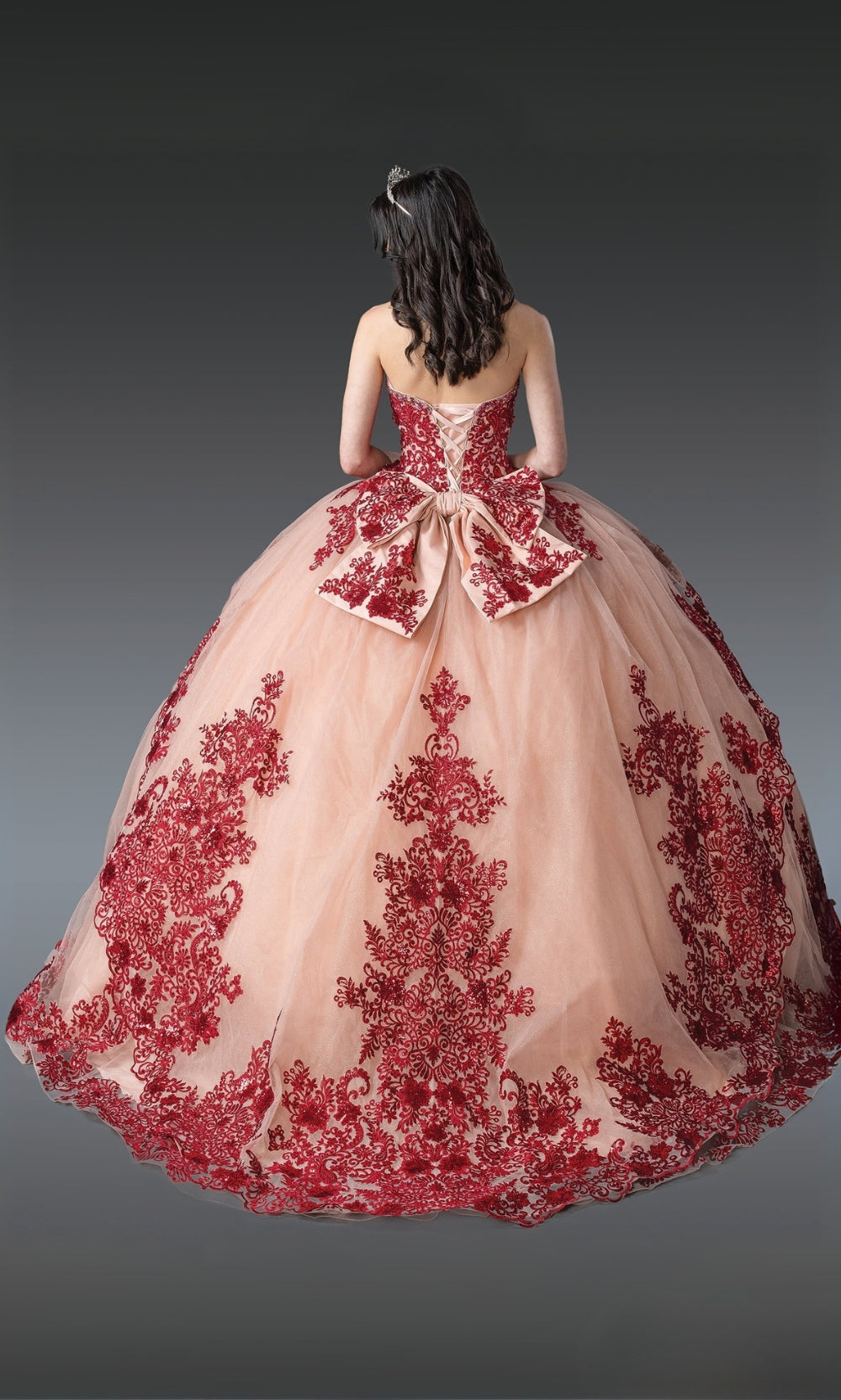 Pink ball gown with red floral embroidery on a gray background