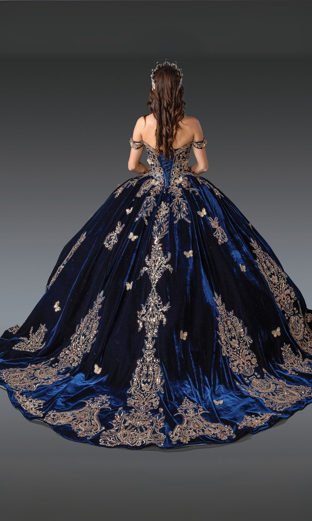 Navy blue evening gown with intricate gold embroidery on a gray background