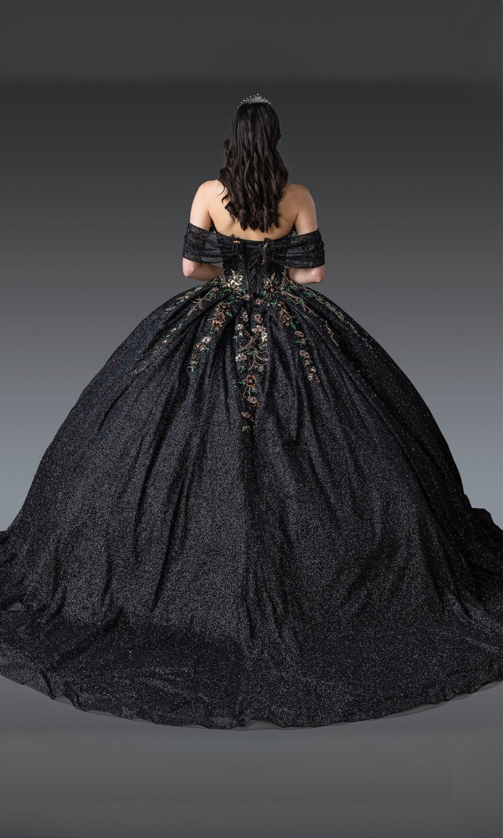 Black ball gown with intricate detailing on a gray background