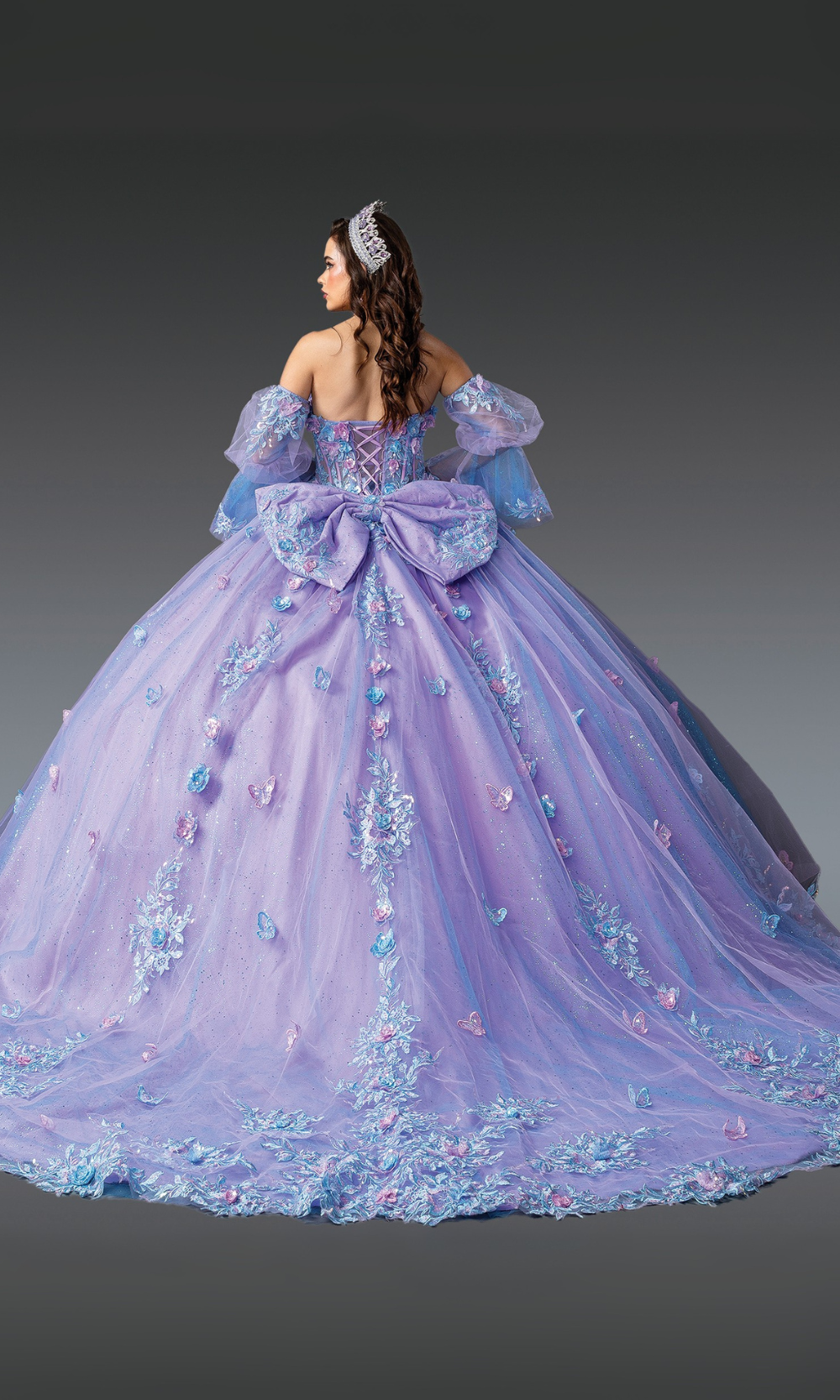 Woman wearing a lavishly decorated purple gown with floral details on a gray background