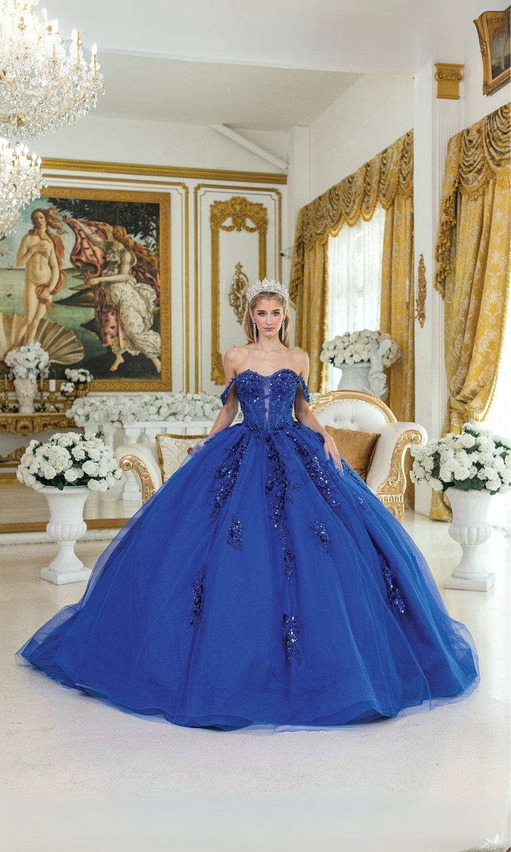 Woman in a blue ball gown standing in an ornate room with gold accents and classical art.