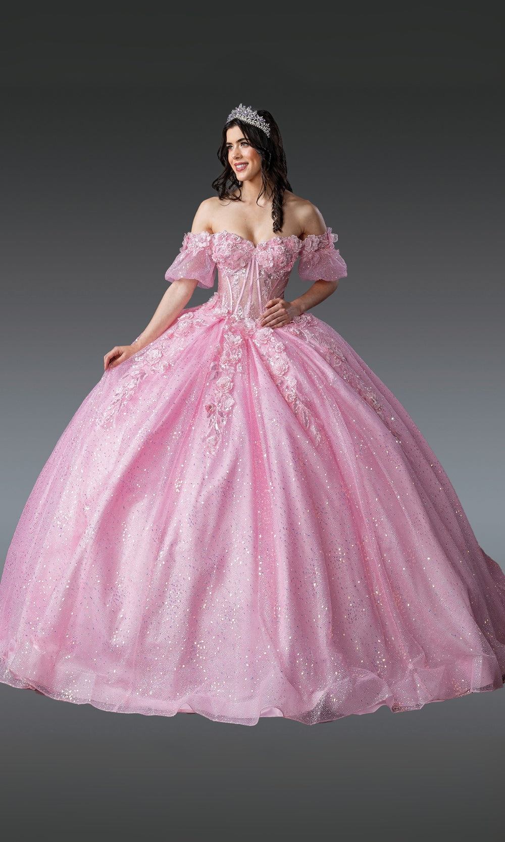 Woman wearing a pink ball gown with lace details on a gray background