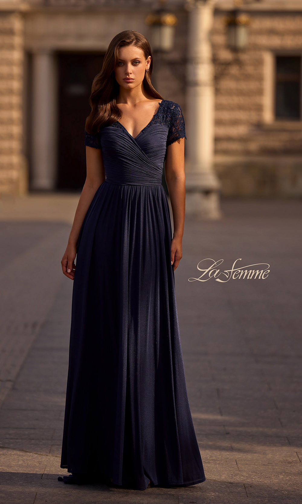 Woman wearing a dark blue evening gown in an outdoor setting with 'Le Fonne' branding.
