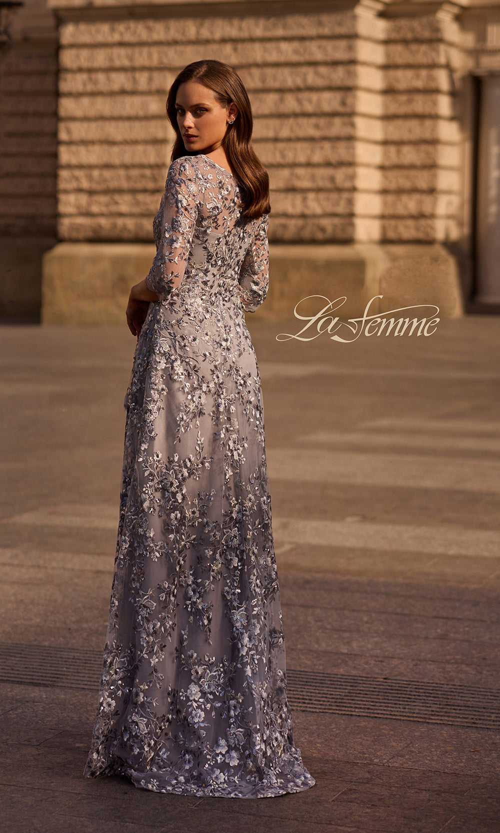 Woman in a floral evening gown standing in front of a classical building.
