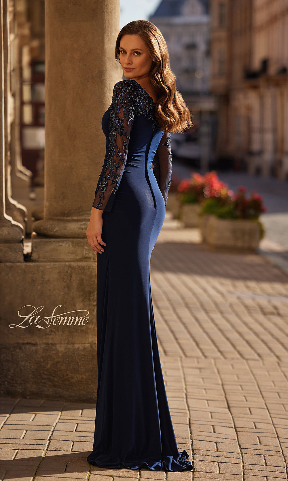 Woman in a blue evening gown standing on a street with 'La Femme' branding.