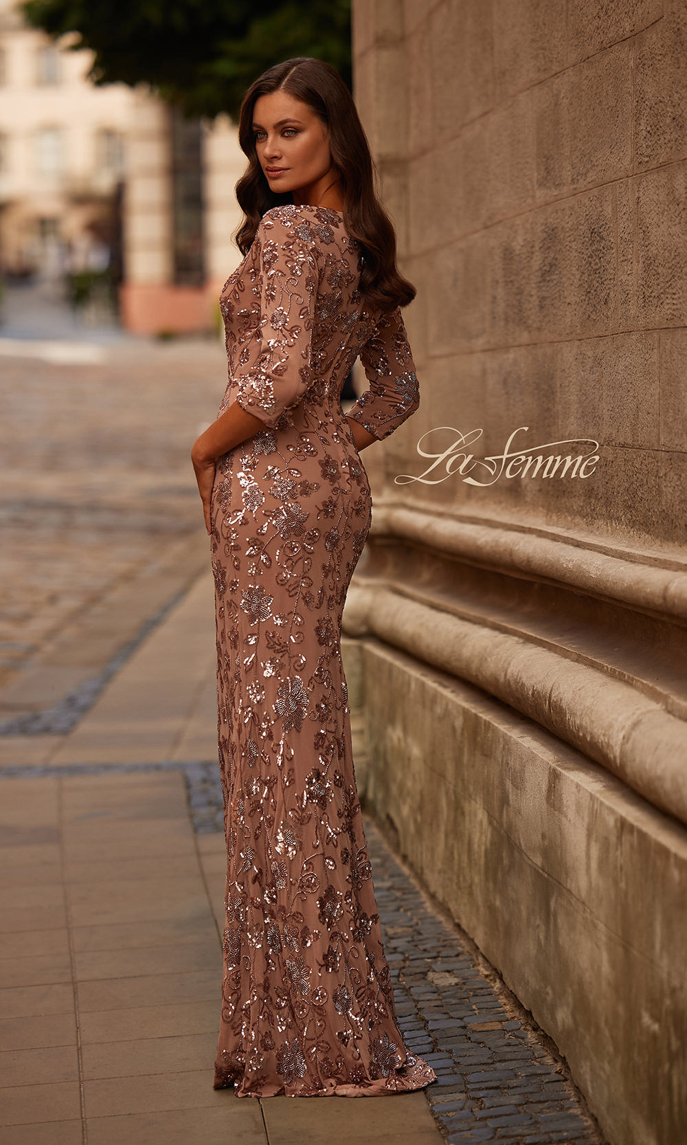 Woman in a rose gold sequin dress standing against a textured wall with 'La Femme' branding.