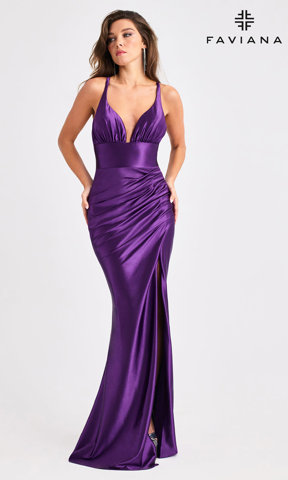 Woman wearing a purple evening gown with a deep neckline and slit on a white background, branded 'Faviana'.