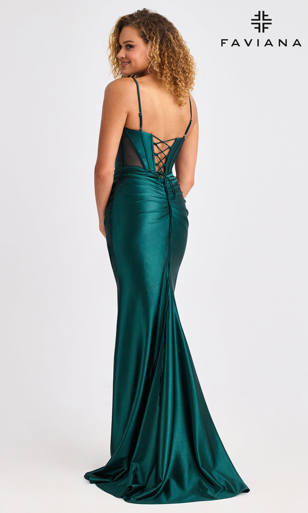 Woman wearing a green evening gown with lace-up back, on a white background with Faviana branding.