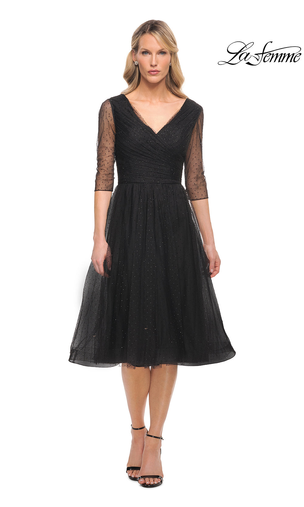 Woman wearing a black dress with sheer sleeves on a white background