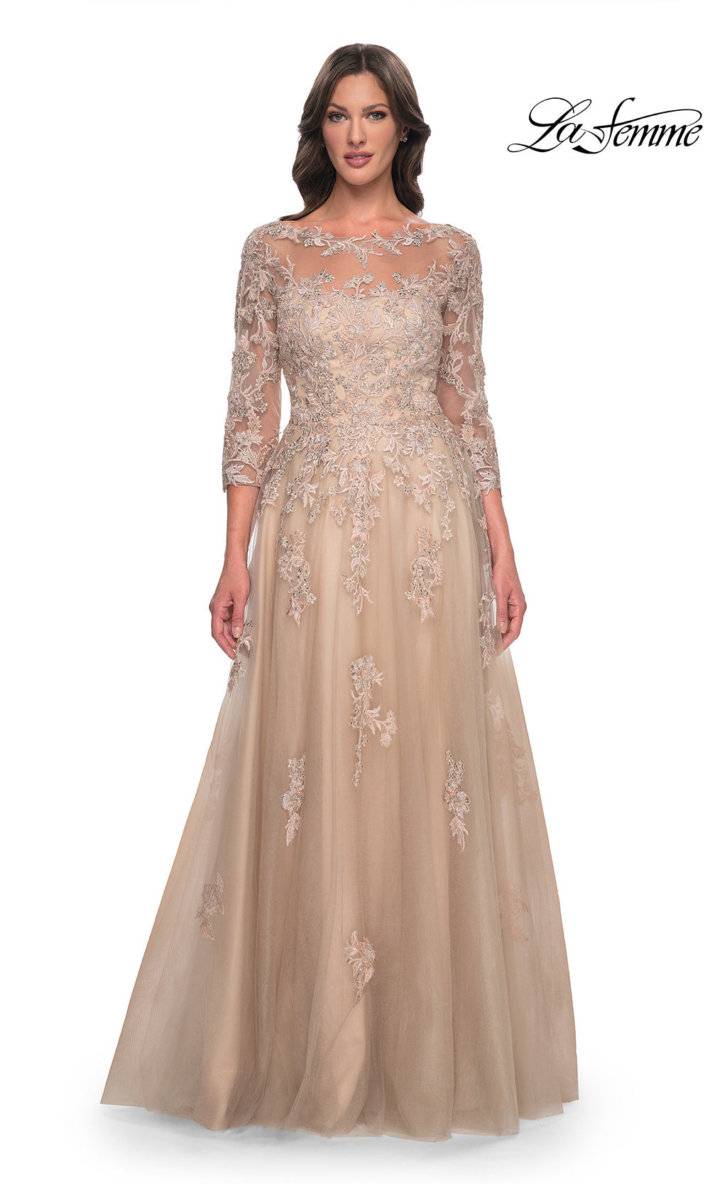 Woman wearing a beige evening gown with floral lace details on a white background