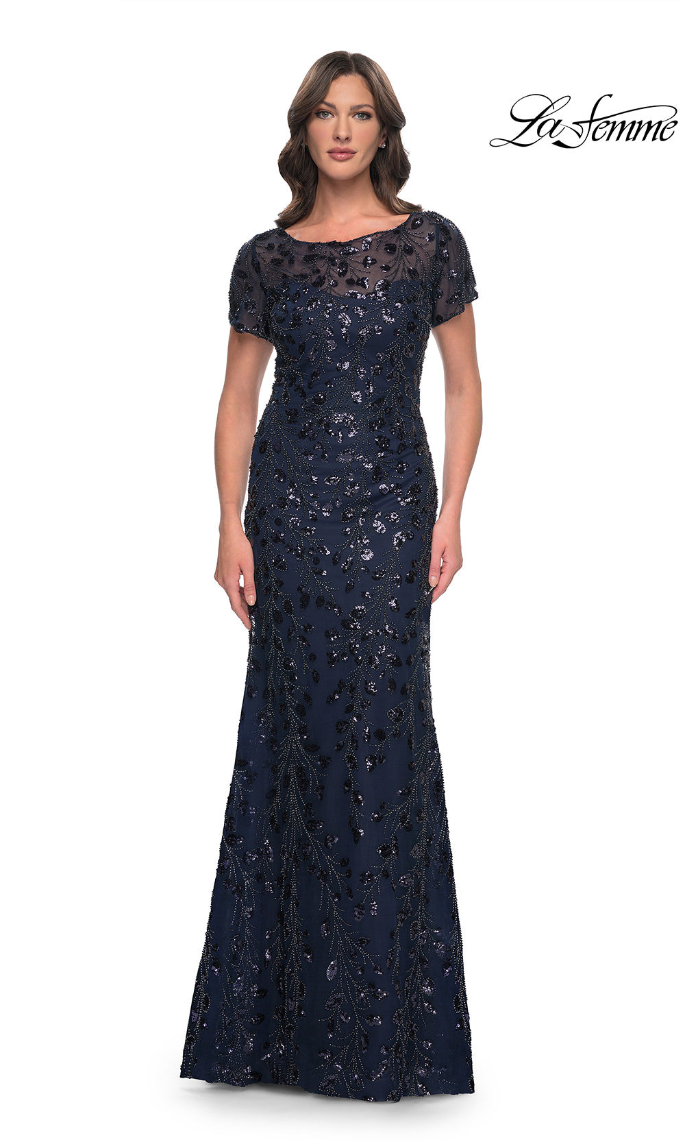 Woman wearing a navy blue evening gown with lace details on a white background