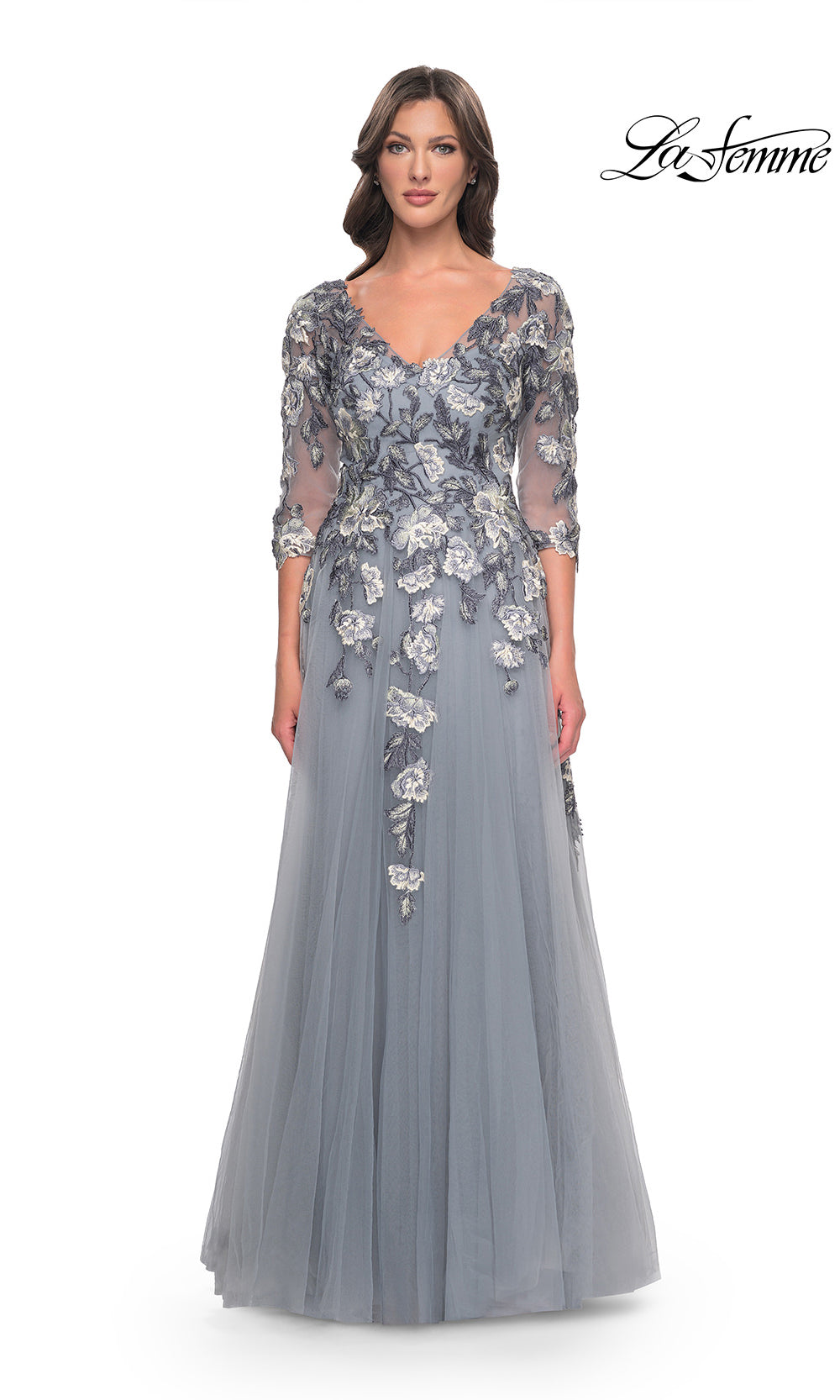 Woman wearing a gray evening gown with floral embroidery on a white background
