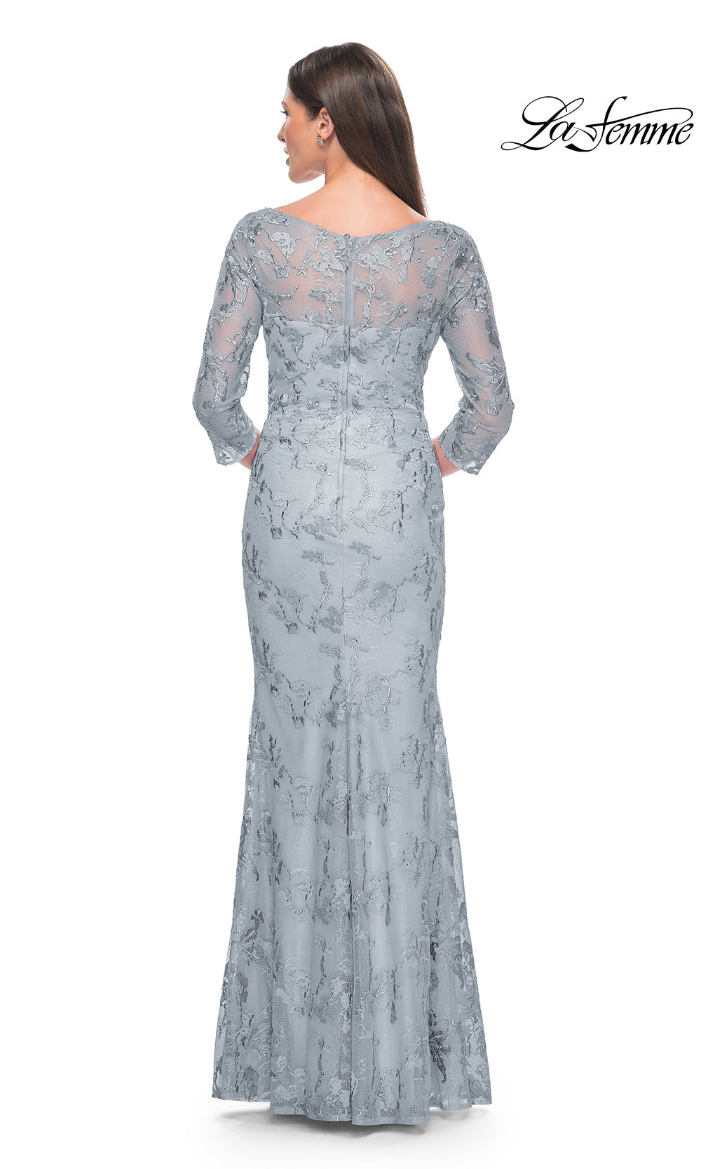 Woman wearing a long, lace evening gown on a white background