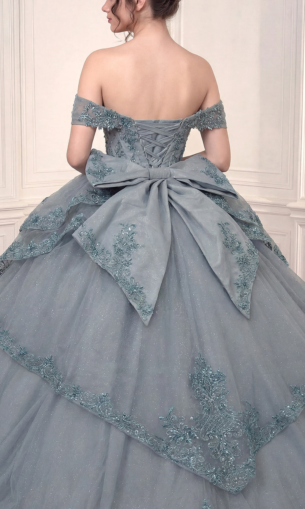 Ladivine 15729 Dusty Blue back view showing full corset lace-up closure, cathedral train volume, and overskirt layers, debut ball gown, quinceanera ready