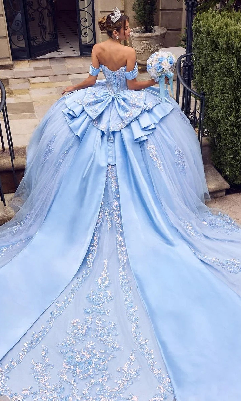 Ladivine 15745 Light Blue back view quinceañera ballgown showing lace-up corset back, tiered satin bow, cathedral train, debut ball gown