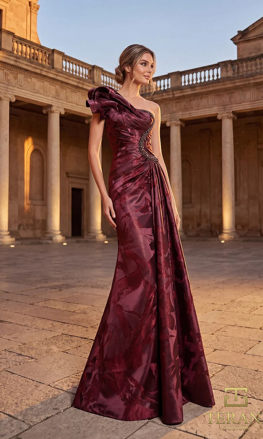Terani Couture 262E7376 Burgundy formal evening dress front view with one-shoulder ruffled bow neckline, tonal floral jacquard draped A-line gown, black tie event dress