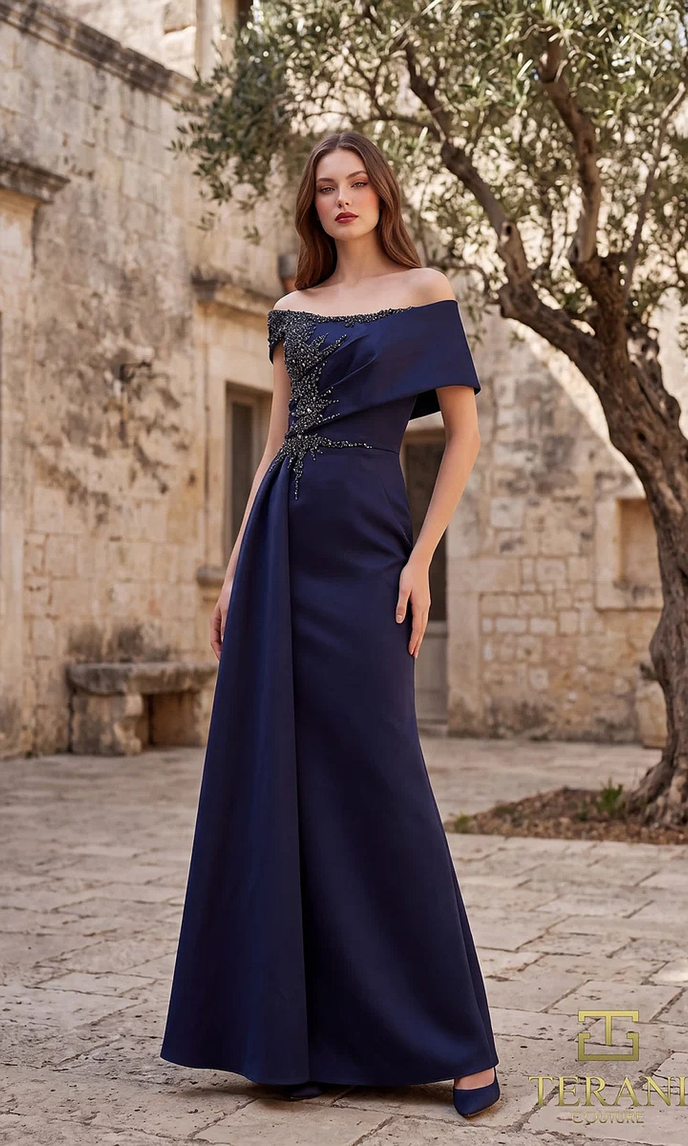 Terani Couture 262M7278 Navy mother of the bride dress front view with off-shoulder folded neckline, beaded pleated bodice, satin column with draped overskirt, mother of the bride styling
