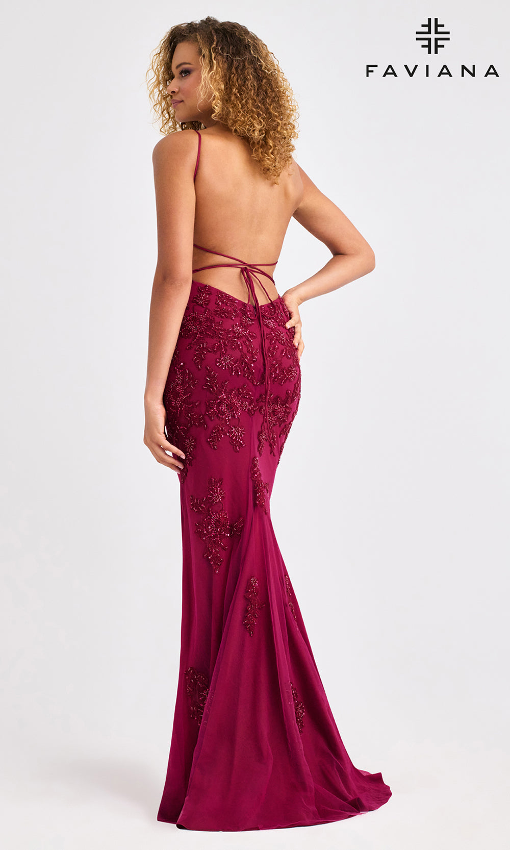 Woman wearing a burgundy evening gown with lace details, backless design, and open front on a white background. Brand 'Faviana' visible.