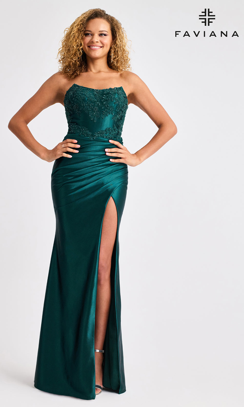 Woman wearing a green strapless gown with a slit on a white background, branded 'Faviana'.