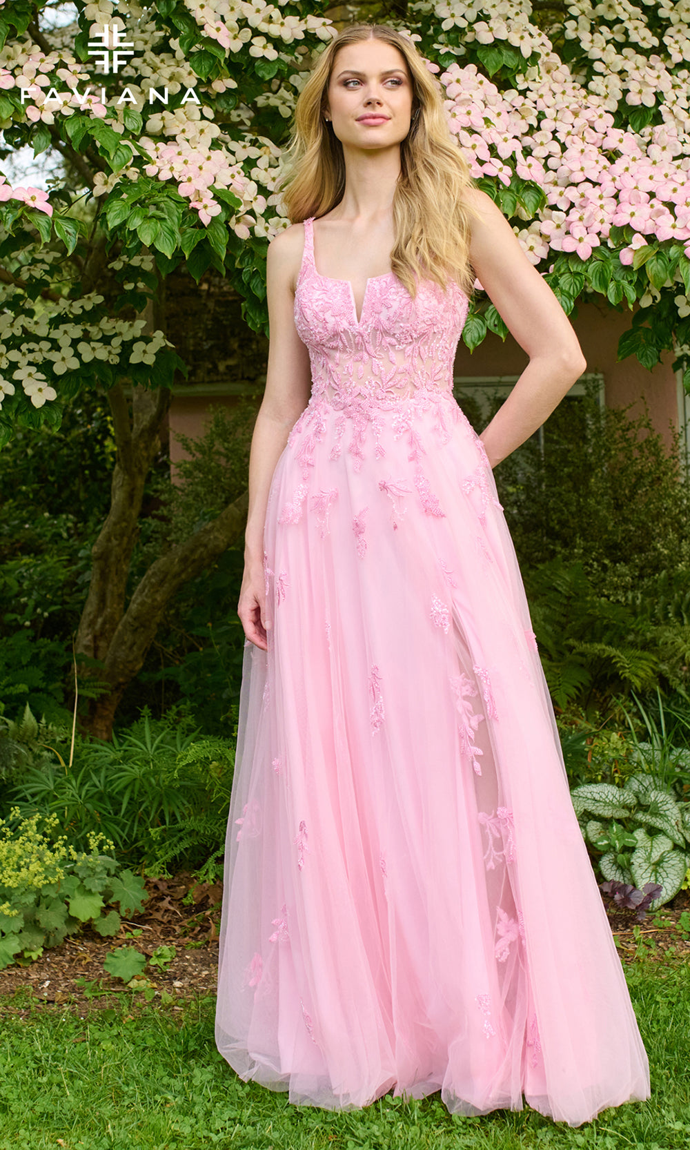 Woman in a pink dress standing in a garden with flowers and greenery.
