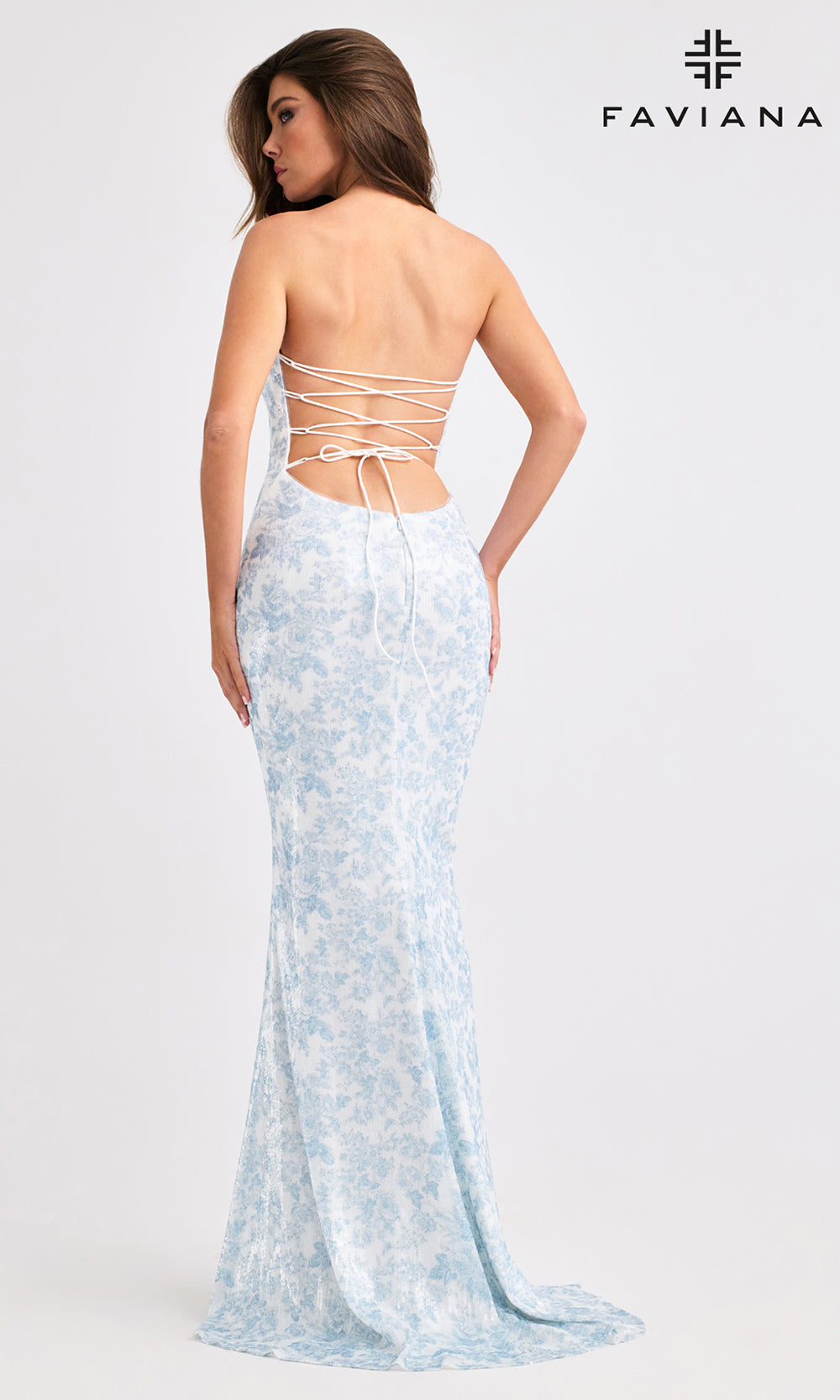 Woman wearing a light blue lace dress with a backless design, standing against a white background. FAVIANA brand logo is visible.