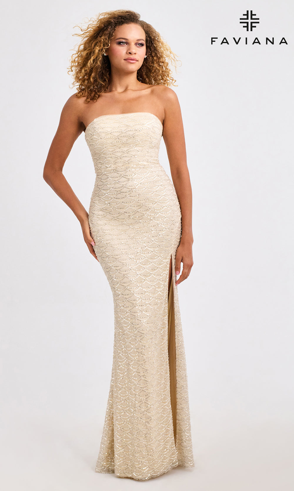Woman wearing a strapless, long, beige dress with a slit on a white background, branded 'Faviana'.
