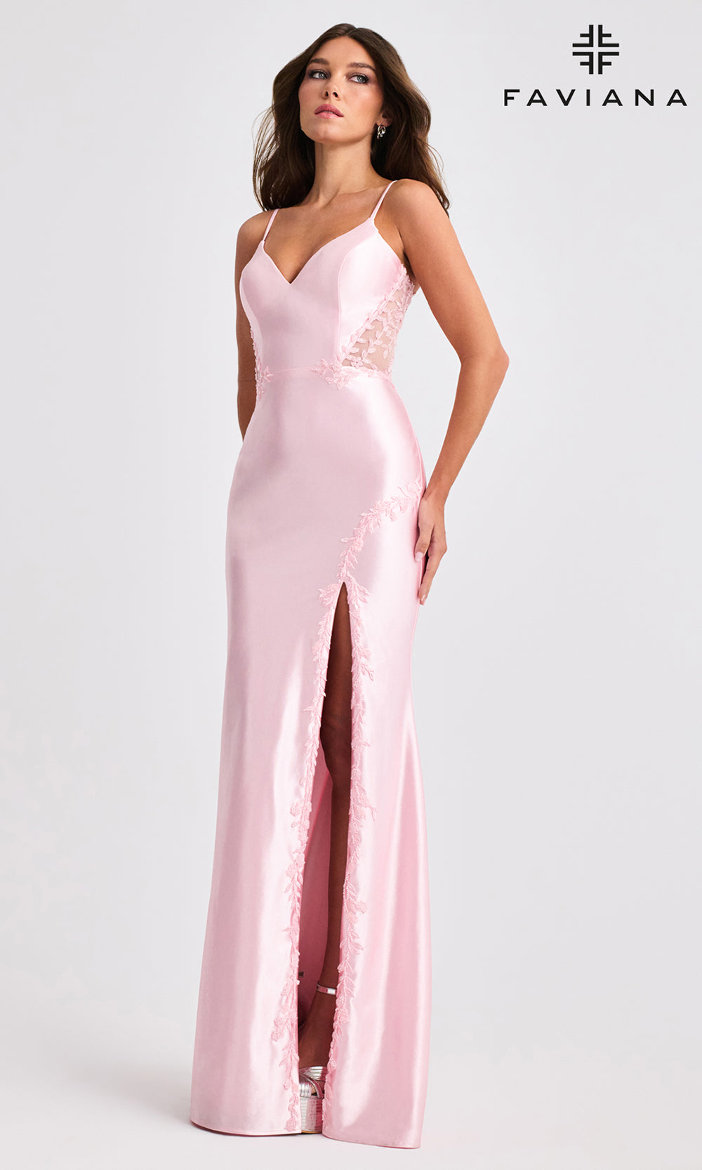 Woman wearing a pink evening gown with a slit on a white background, branded 'Faviana'.