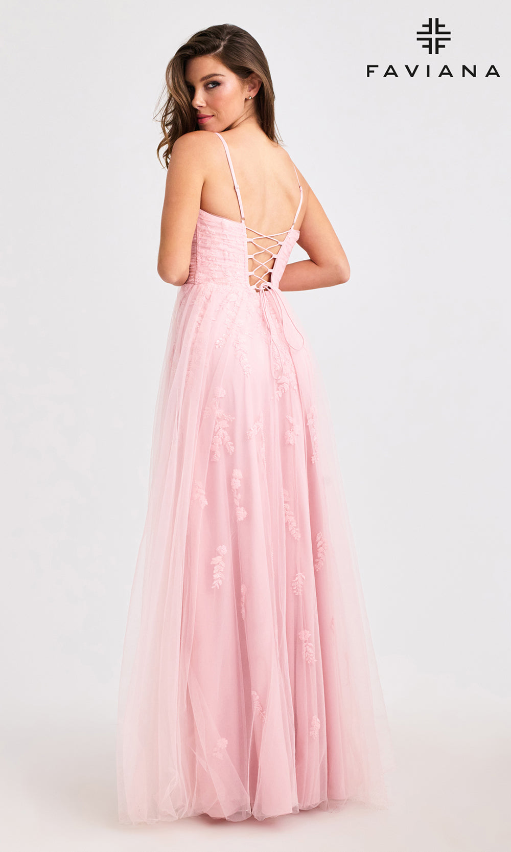 Woman wearing a pink dress with lace-up back, branded 'Faviana', on a white background