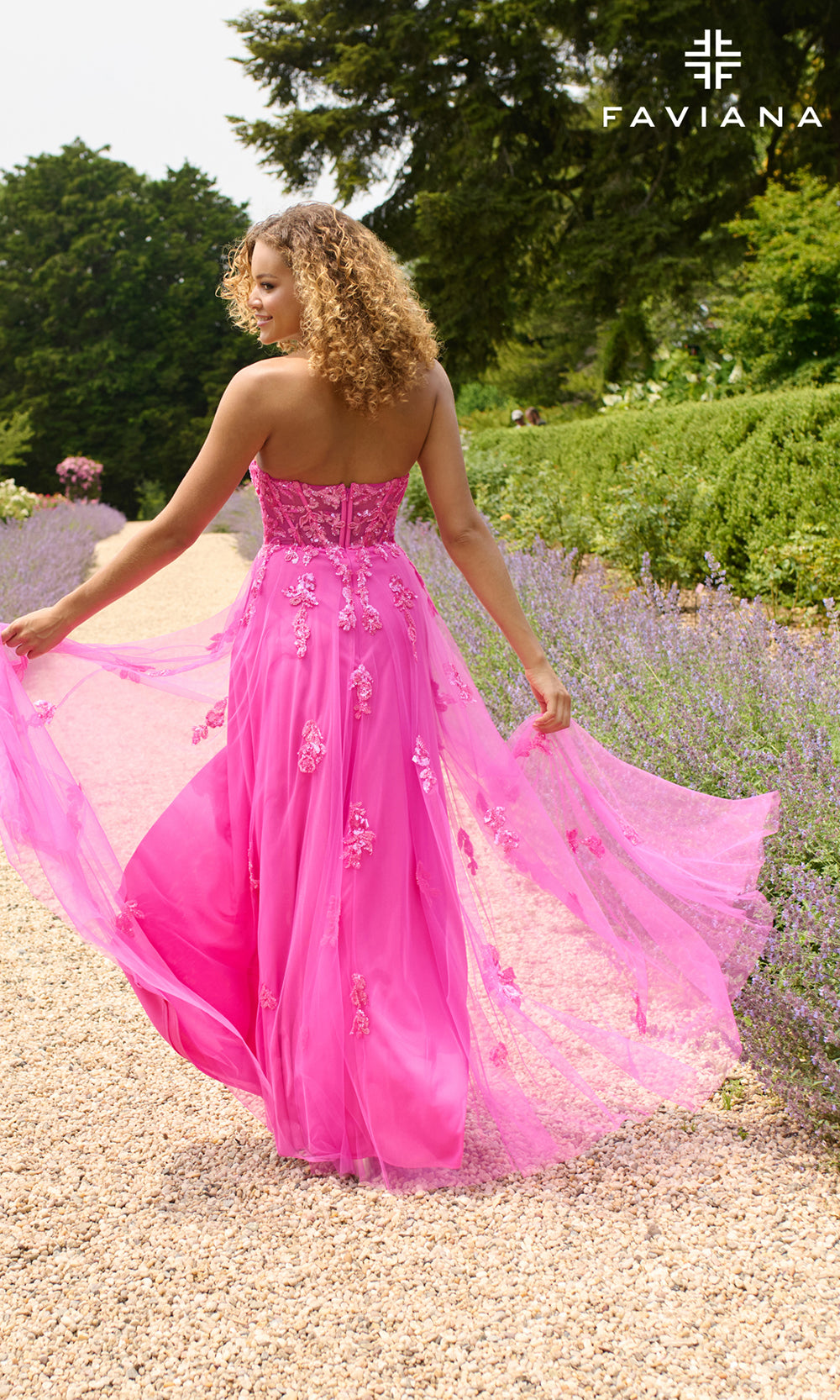 Woman in a pink dress standing in a garden with 'Faviana' branding.