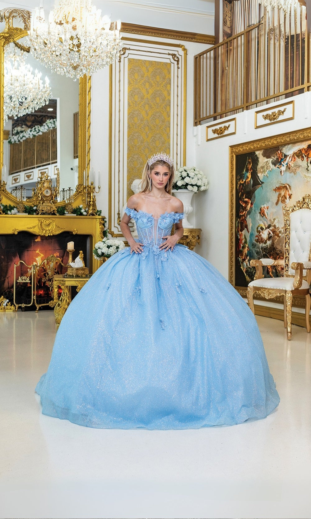 Woman in a light blue ball gown standing in an opulent room with gold decor and paintings.