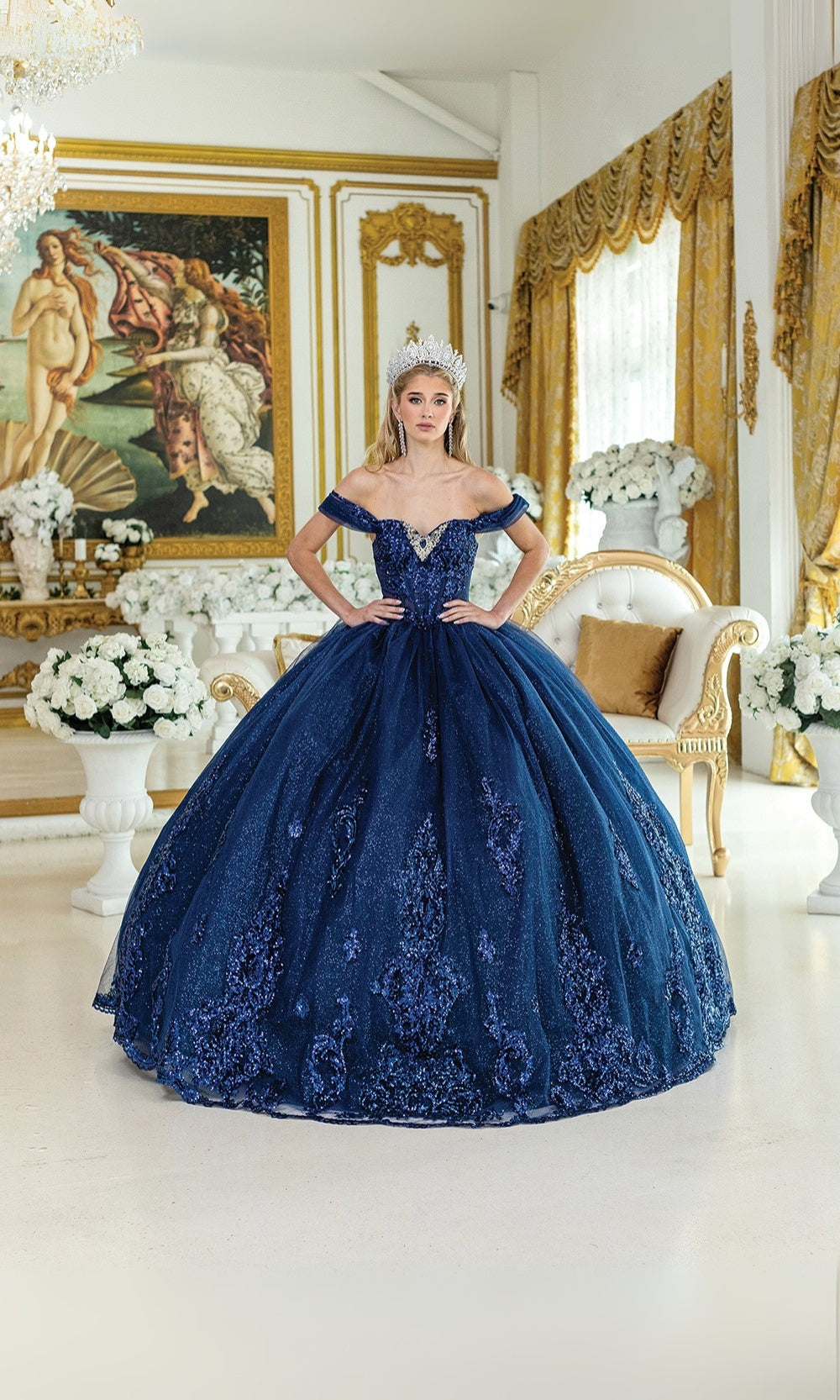 Woman in a navy blue ball gown standing in an elegant room with gold accents and artwork.