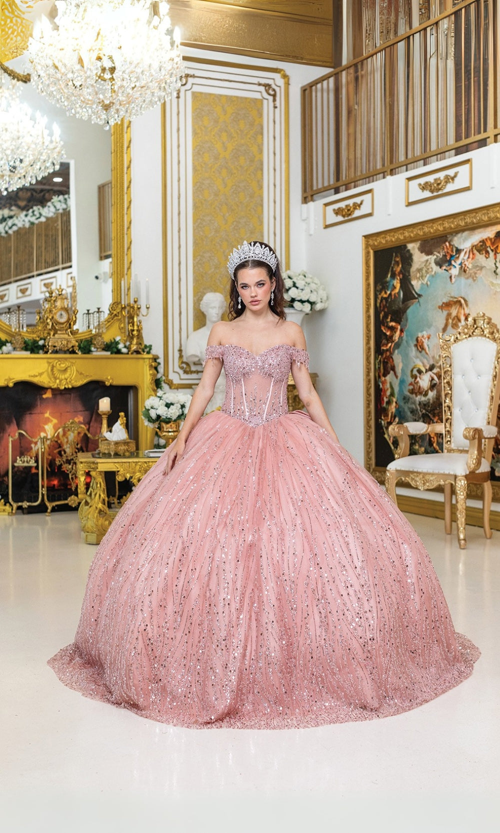 Woman in a pink gown standing in an opulent room with gold decor.
