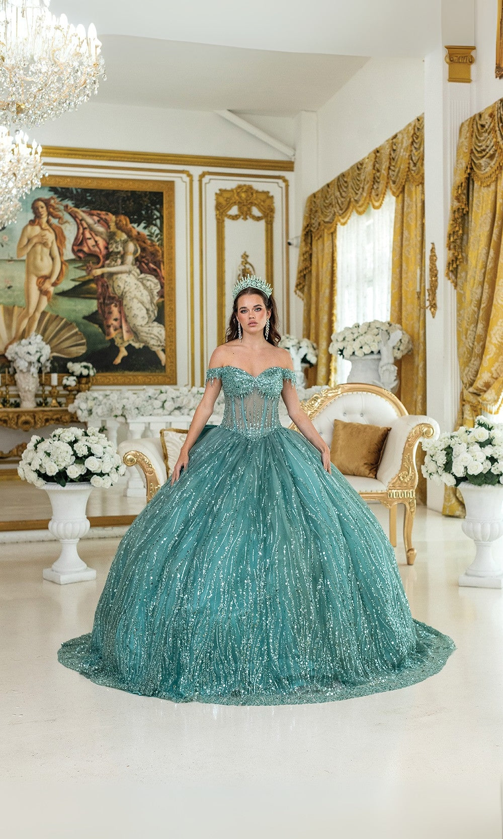 Woman in a teal evening gown standing in an elegant room with classical decor.