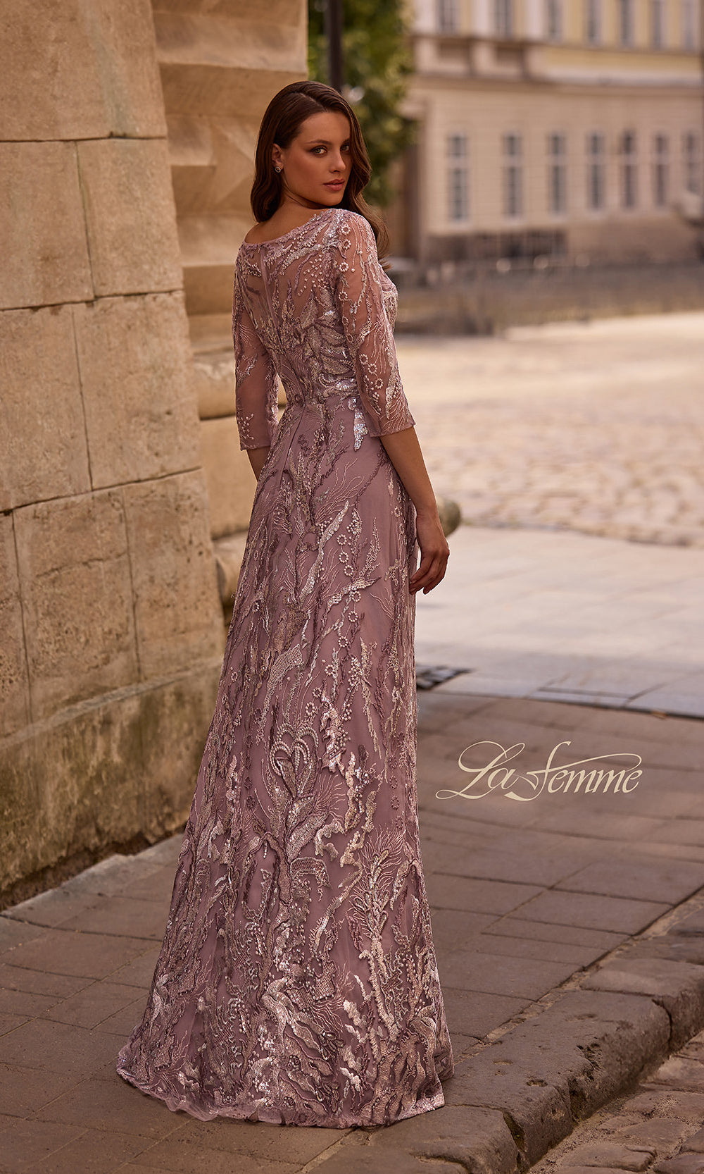 Woman in a long, elegant dress standing on a stone path with a blurred background