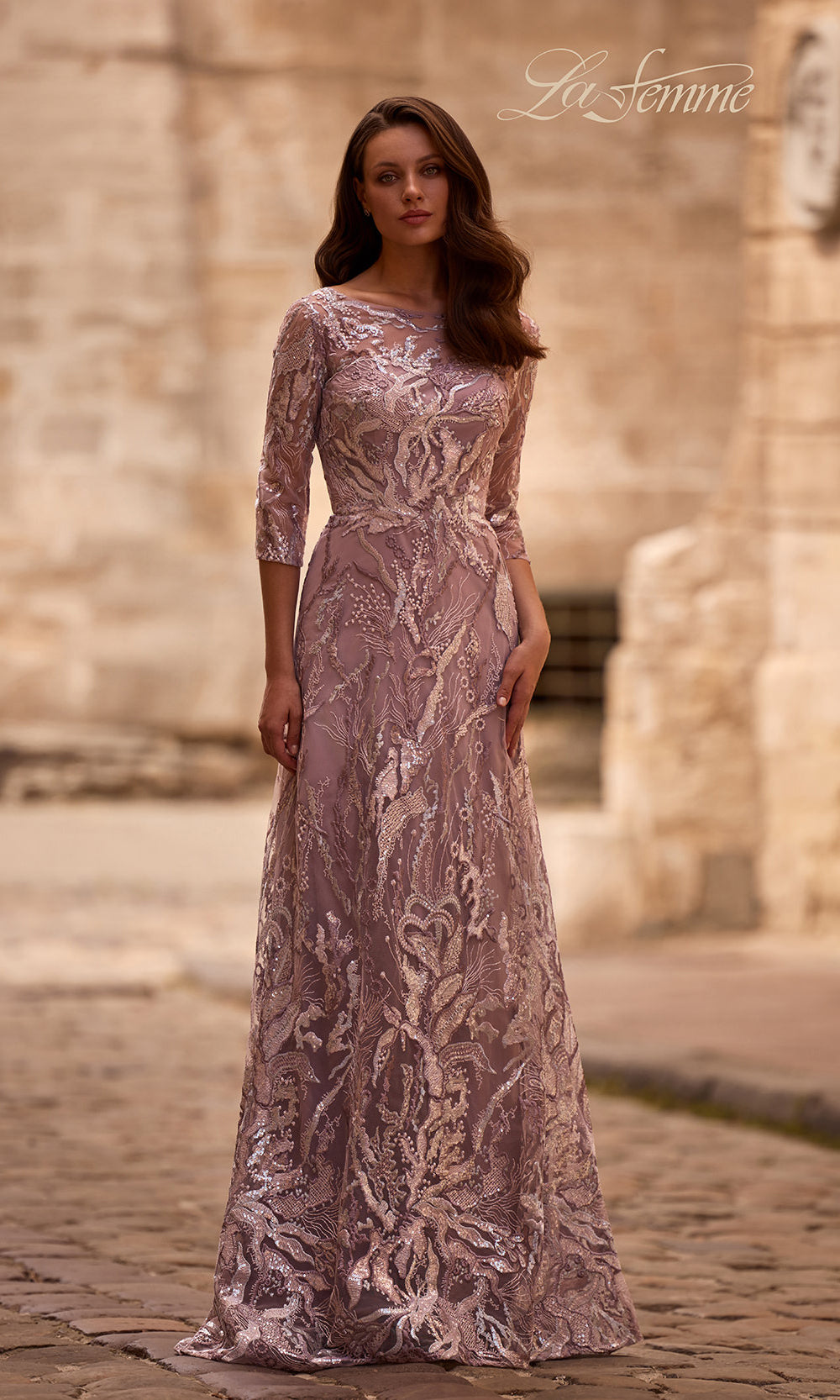 Woman wearing a long, patterned dress standing in front of stone architecture.