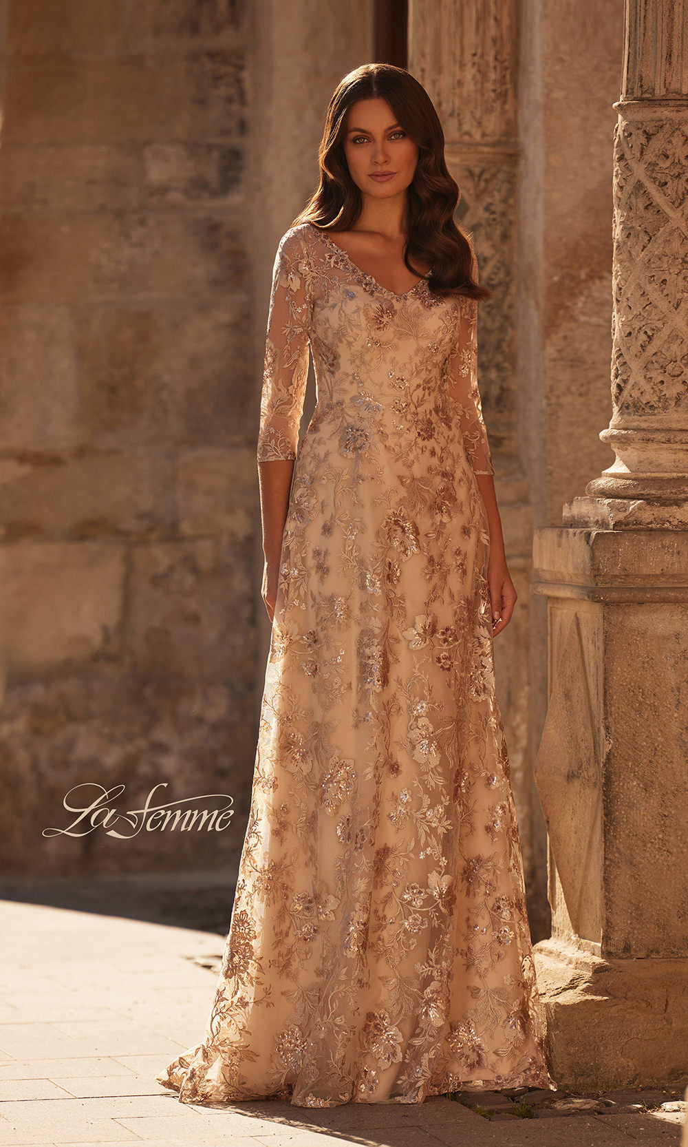 Woman in a long, elegant dress standing in front of stone architecture