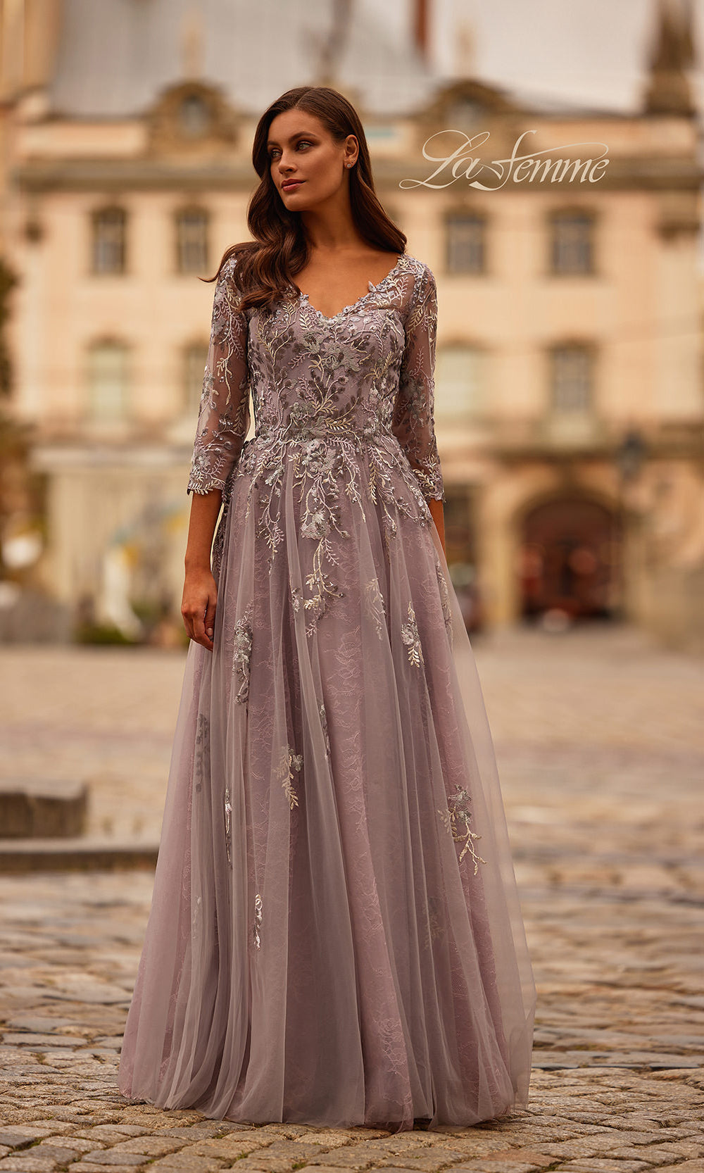Woman wearing a long, elegant dress with lace details in an outdoor setting.