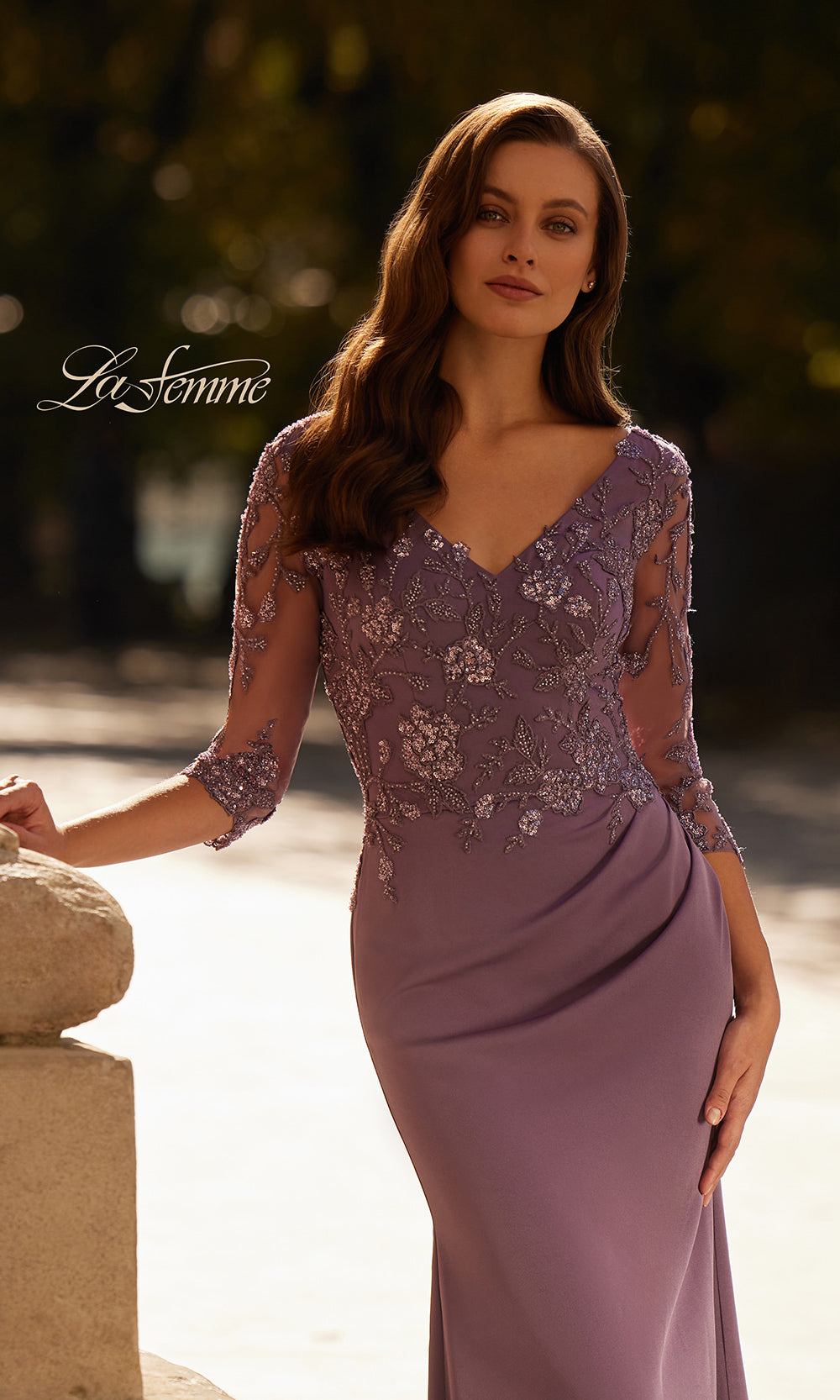 Woman wearing a purple evening gown with lace details, standing outdoors.