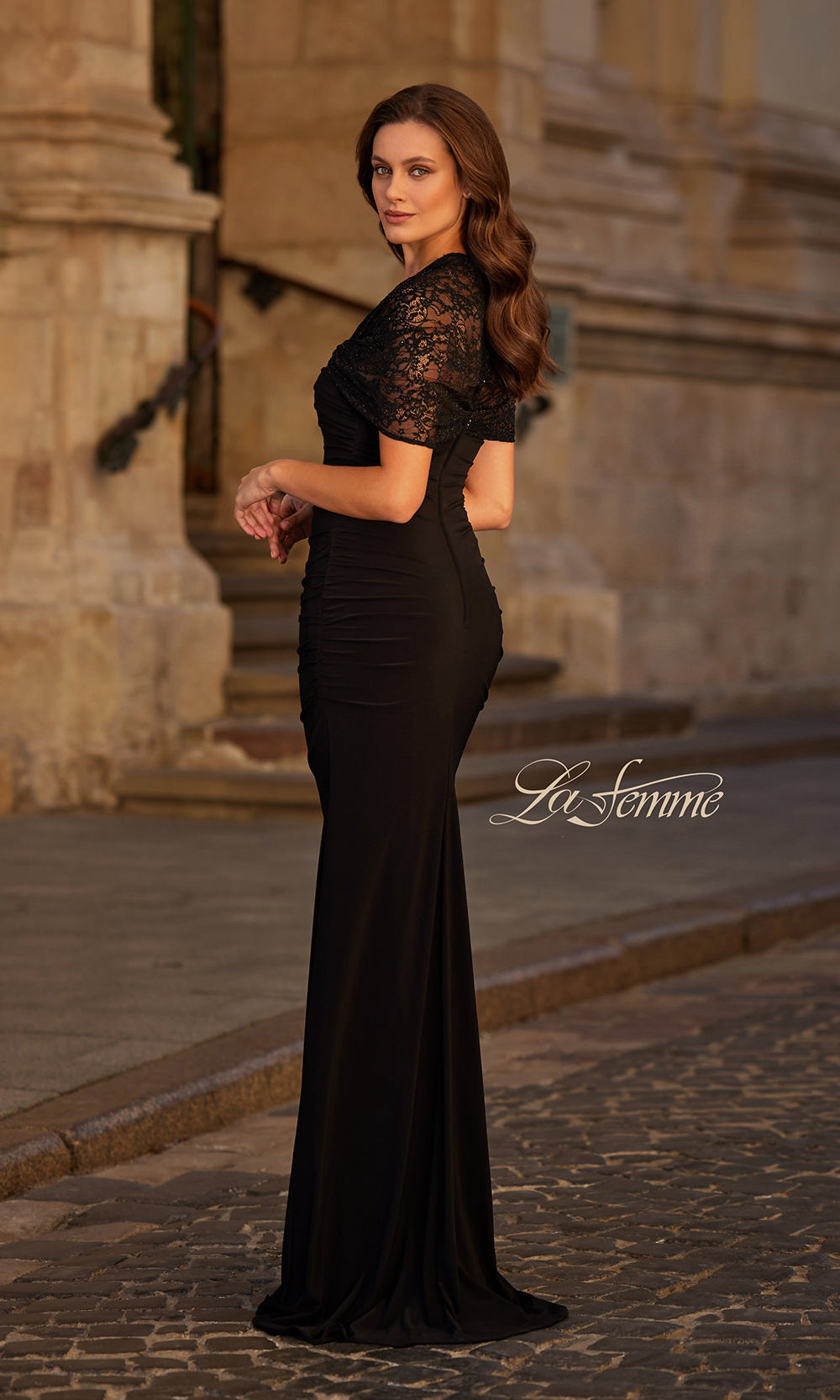 Woman in a black evening gown standing in an outdoor setting with 'La Femme' branding.