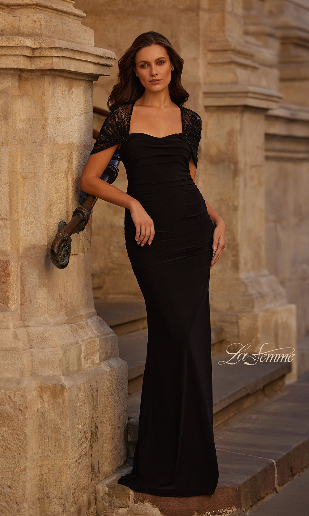 Woman in a black evening gown standing against stone architecture